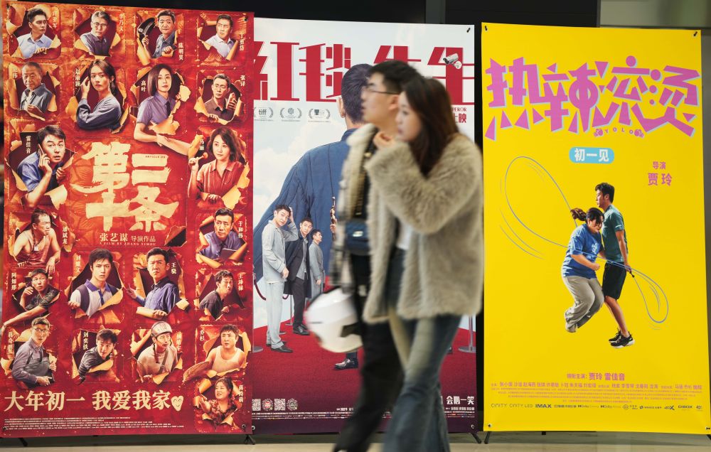 2月17日，在沈阳一家影院，观众从海报前经过。新华社记者李钢摄