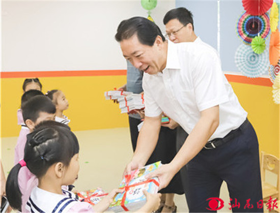 杨绪松(右一)向市第三幼儿园小朋友赠送礼物。记者 孙实 摄