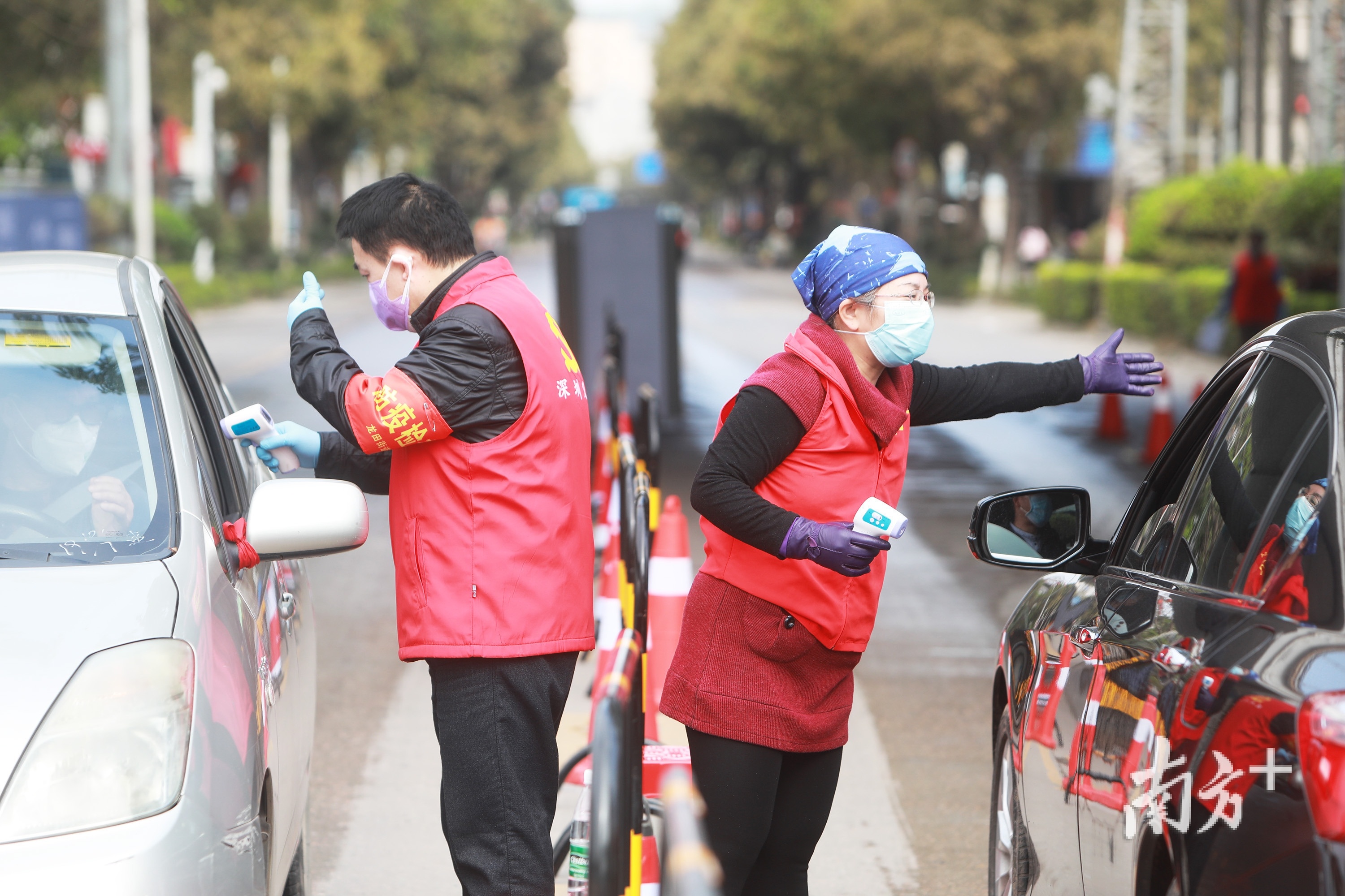 深圳市坪山区龙兴南路，工作人员对过往的车辆内人员测量体温。南方日报记者 朱洪波 摄 