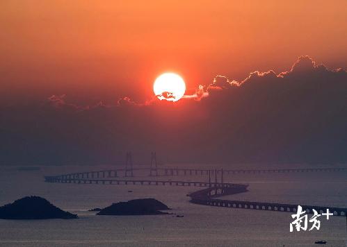 △2018年5月22日，太阳从香港大屿山后升起，港珠澳大桥犹如一条巨龙蜿蜒盘绕在海面上。