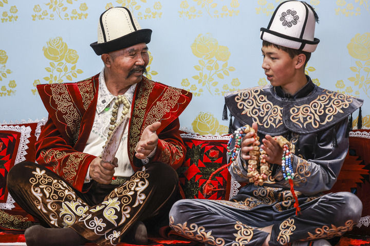 《玛纳斯》国家级非物质文化遗产代表性传承人江努日·图日干巴依(左)教徒弟演唱《玛纳斯》(2025年4月21日摄)。新华社记者 王菲 摄