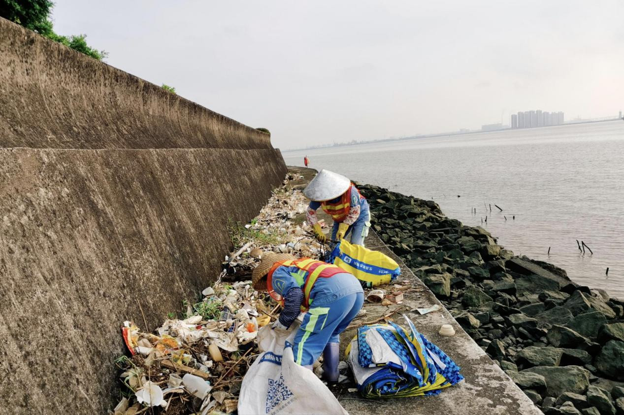 雨后环卫工人清理海岸边垃圾