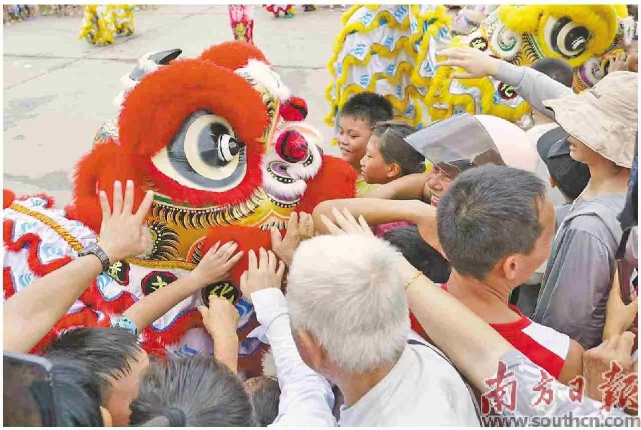 湛江遂溪醒狮与游客群众互动，大家都摸摸狮头寓意沾好运。陈文 摄