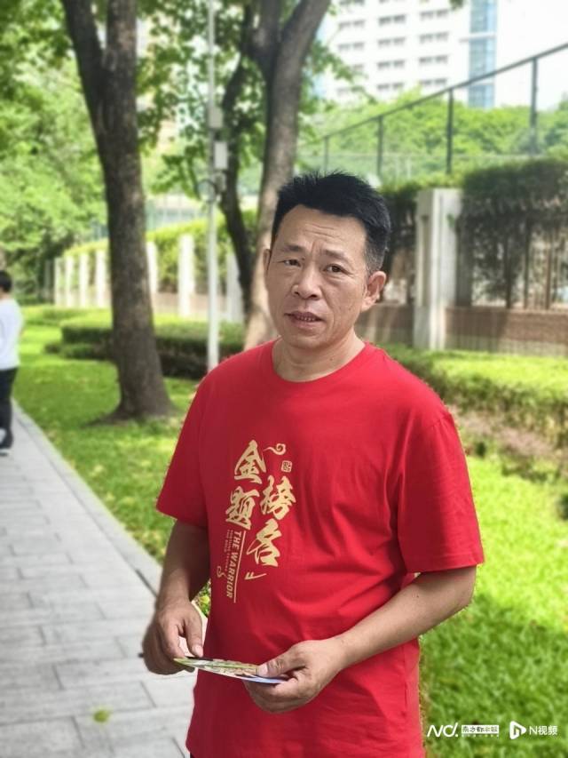 华附考点外，一位特意从浙江来陪儿子高考的吴爸爸身穿红衣早早地在门口等候。