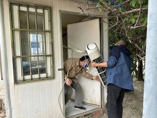 工作人员将岗亭内的空调拆卸后搬出。 工作人员将岗亭内的空调拆卸后搬出。
