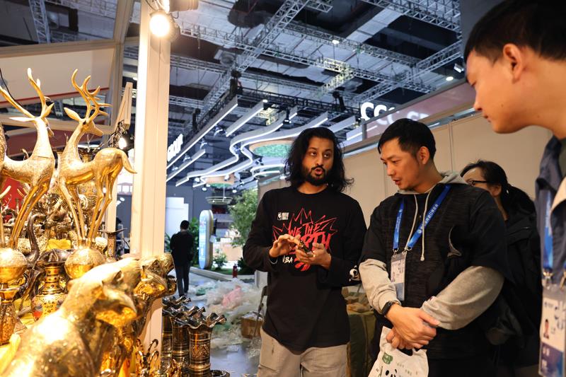 △一名巴基斯坦展商(左)在布置进博会展位时与工作人员交流。