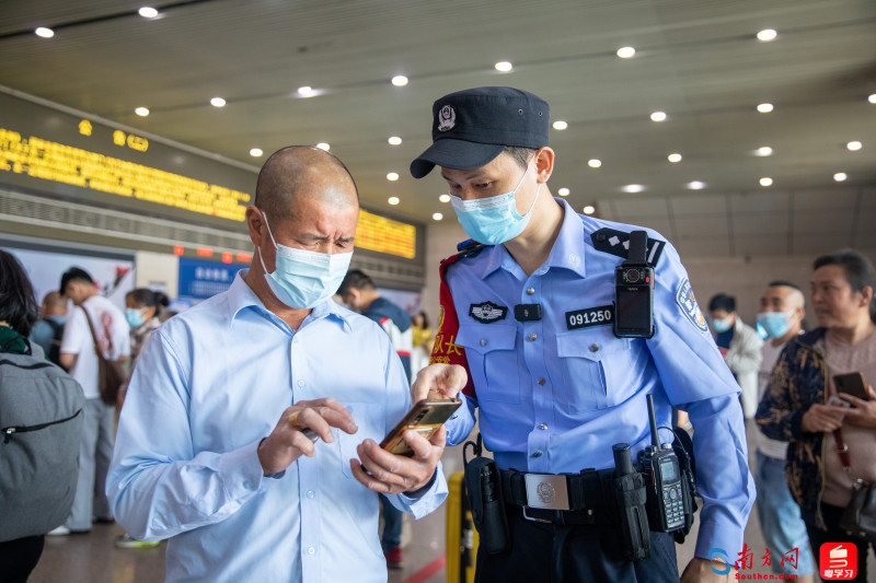 4月30日，广州南站派出所执勤三队队长刘飞在在场巡逻执勤中为旅客解决买票问题。南方日报记者 张令 摄