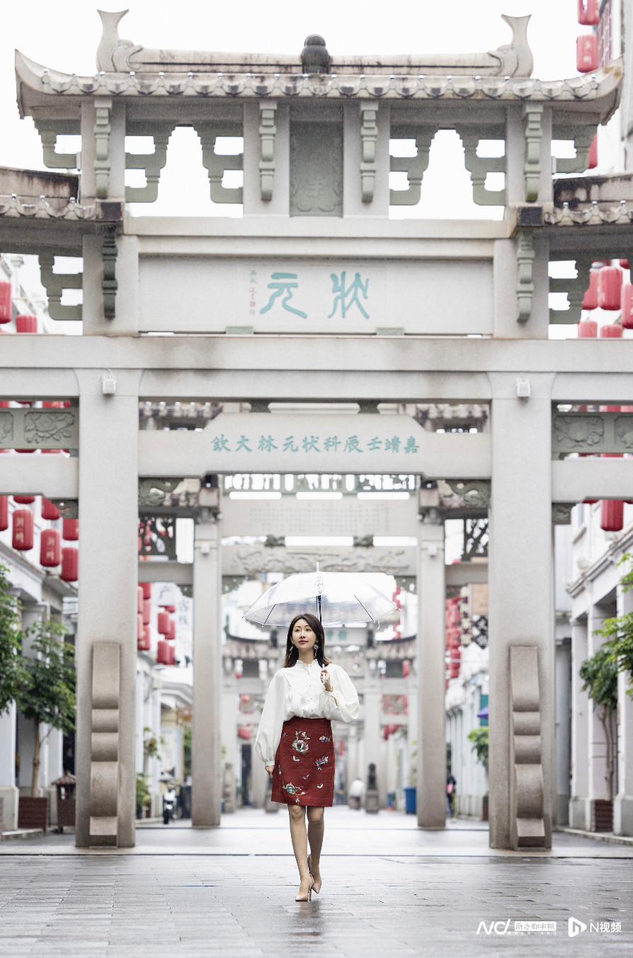 黎贝卡身着香云纱材质潮绣裙，沿着牌坊街步入潮绣康惠芳大师工作室。