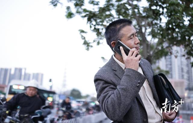 1月29日，嘉禾望岗地铁站口，西装男子夹着公文包、右手打电话。
