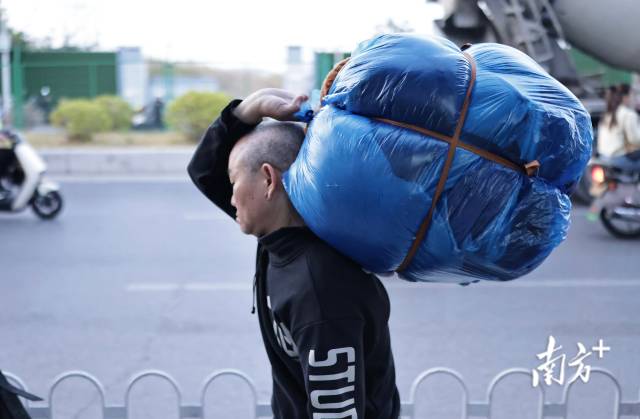 1月29日，嘉禾望岗地铁口，一名男子扛着货物，步履匆匆沿路行走。