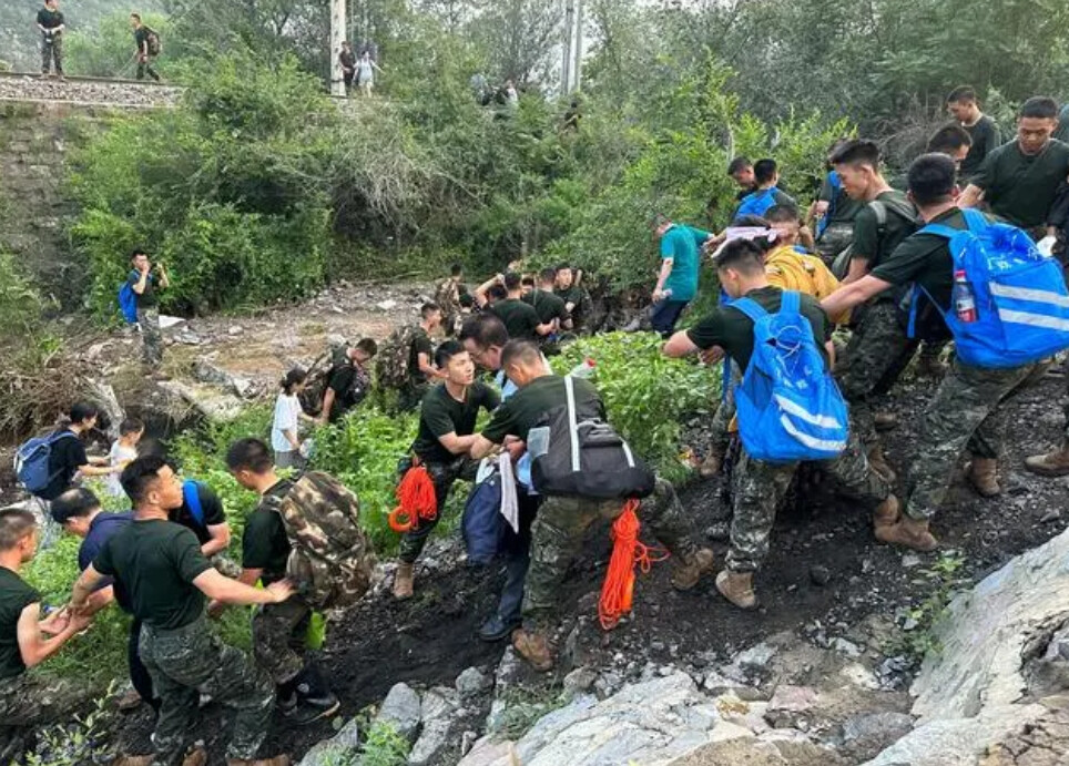 8月2日，Z180次滞留旅客在武警北京总队机动第三支队官兵的帮助下前往转运客车。