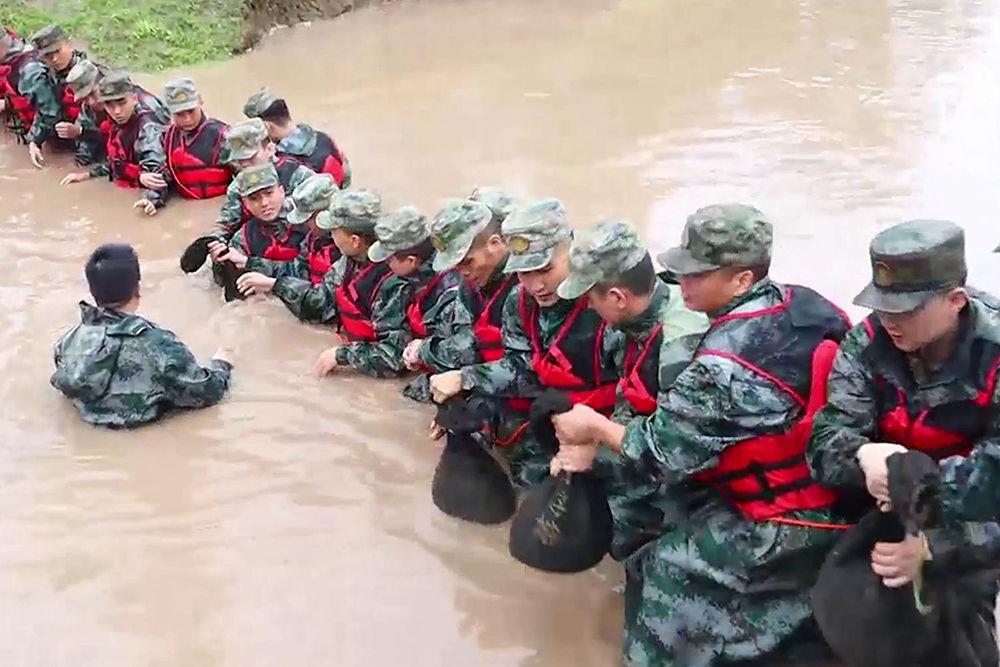 8月2日，中部战区空军某部官兵在北京昌平区沙河镇搭设人墙。