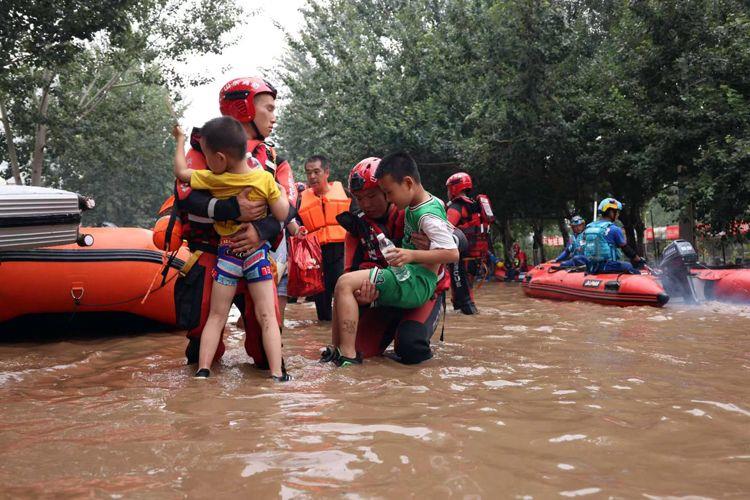 8月3日，河北涿州北二环附近，山东消防救援人员抱着孩子通过积水路段。