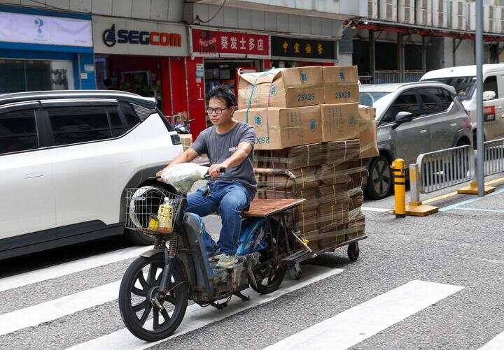 7月22日,一名男子骑着搭载货物的电动车行驶在华强北街头。