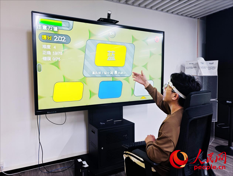 广州琶洲实验室工作人员演示脑机接口设备如何操作专注力训练游戏。人民网 朴馨语 摄