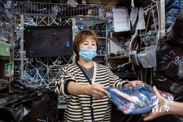 金富丽网络服装批发市场，娅熙大码女装店店长杨文燕正把衣物递给顾客。  南方+ 金镝 拍摄