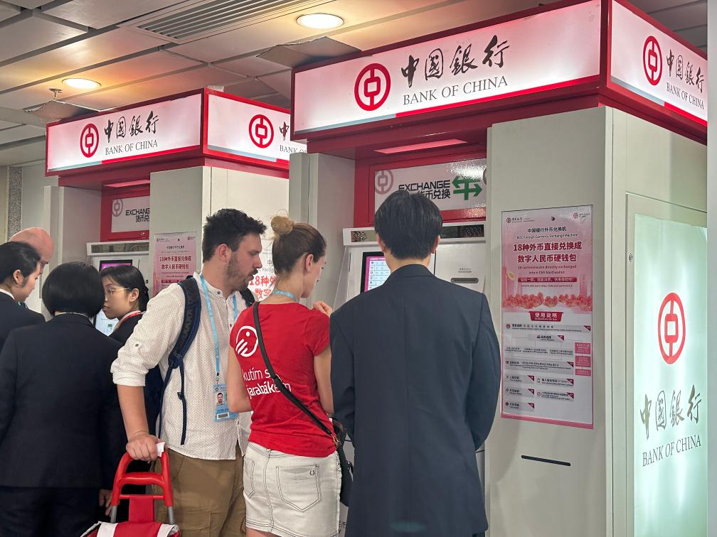 中国银行广交会支行员工在广交会场馆内指引境外采购商办理自助兑换。（黄爱弟 摄）
