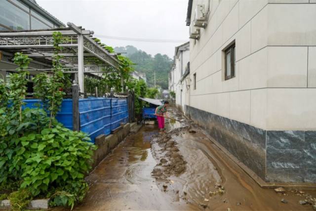 7月27日，密云区石城镇西湾子村，一位居民在清理房屋前河水带来的淤泥。新华社发