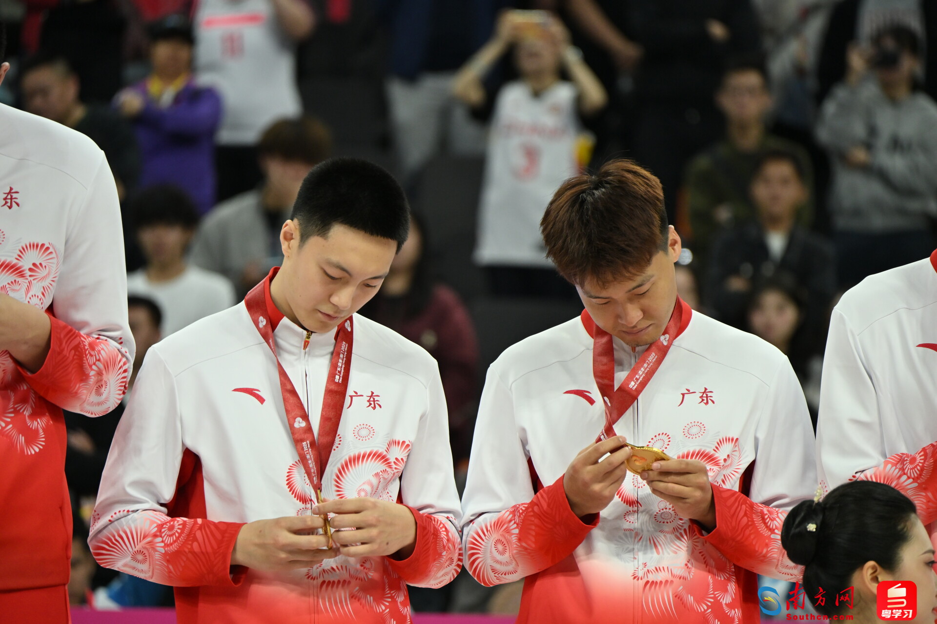 11月12日，广东队勇夺十五运会男篮成年组冠军。颁奖仪式上，胡明轩（左）与赵睿（右）仔细端详奖牌。这是广东男篮时隔12年再次获得该项目金牌。