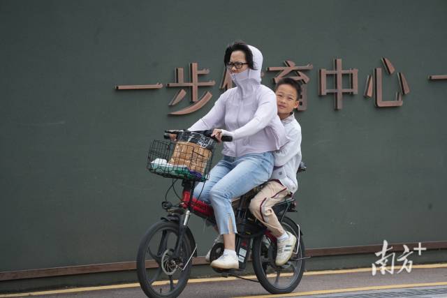 小朋友躲在妈妈的自行车后座避风。