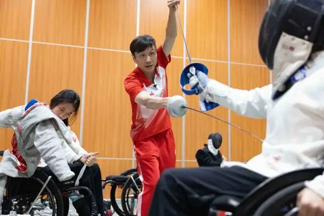 在训练基地中，龙杰正在手把手指导C级运动员出剑的位置。