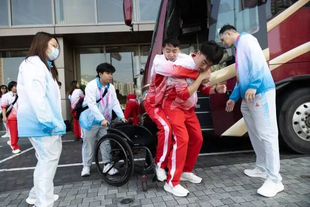 抵达香港酒店后，助教林琪深逐一将大巴上的队员背下来放置在轮椅上。