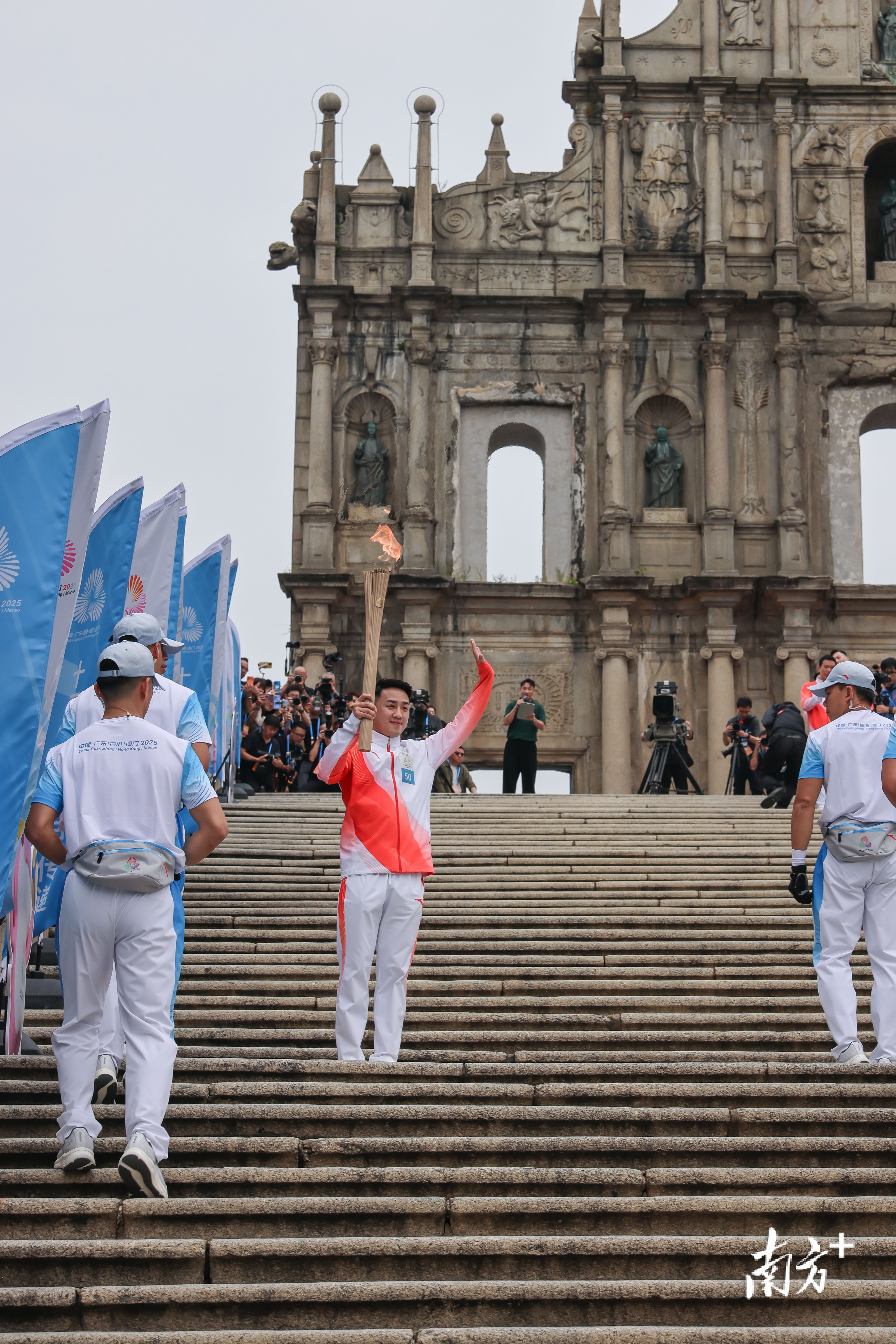 澳门站第五十棒火炬手郭建恒跑上大三巴牌坊并与观众挥手。
