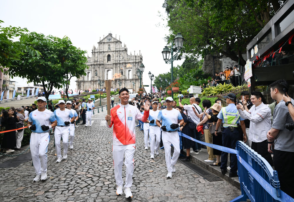 △火炬手罗协铭在澳门大三巴牌坊前进行火炬传递。新华社发（张金加摄）