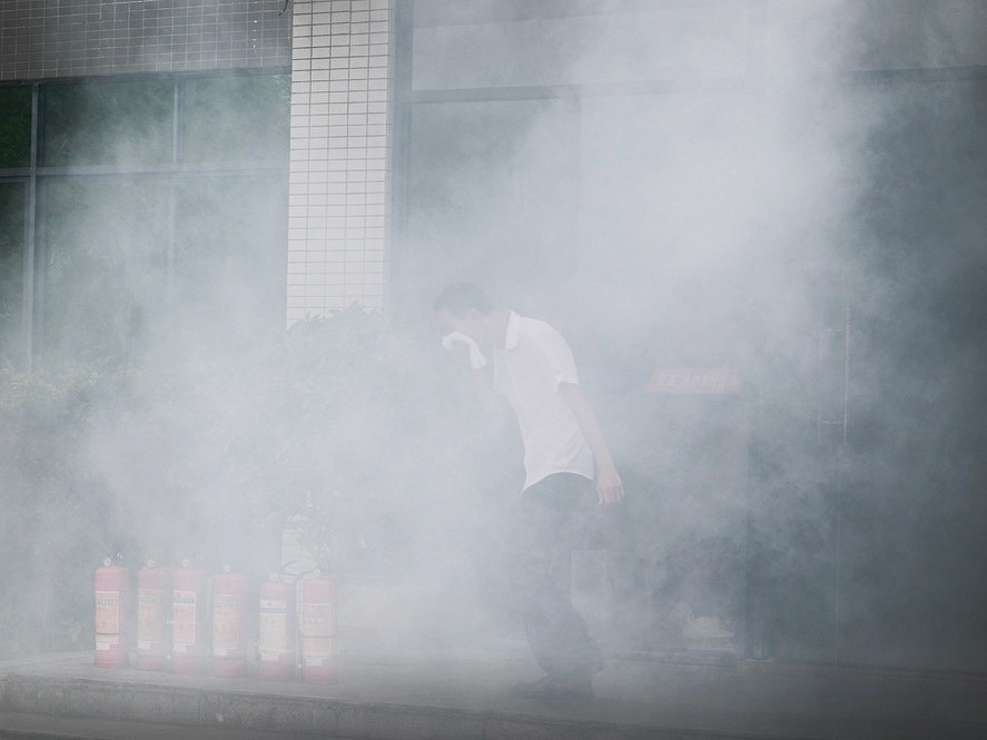 参训人员捂紧口鼻循着预定疏散路线逃生 摄影：段佐斌