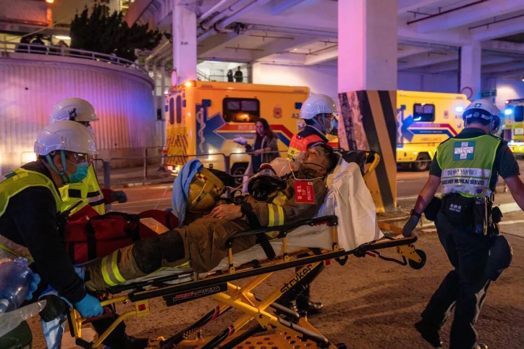 在火灾现场,医护人员用担架将一名消防员紧急送往救护车。(视觉中国 / 图)