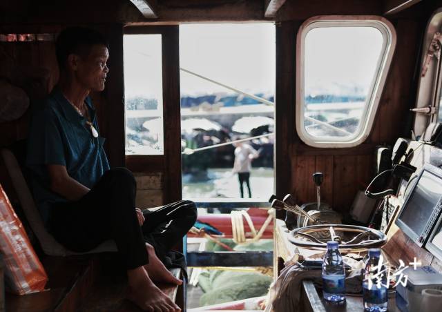 年届六十的老渔民坐在渔船驾驶室。