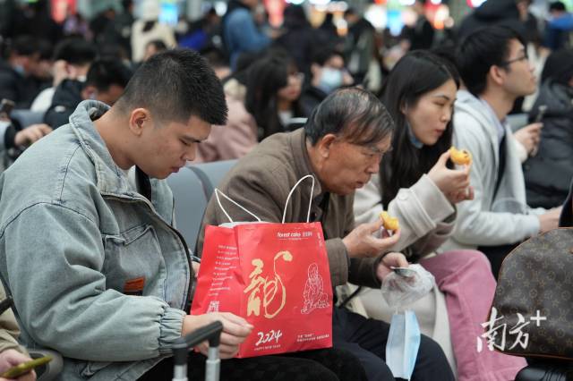 广州南站候车厅内，乘客们在品尝“龙”年点心。