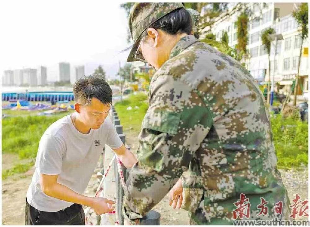 在惠州双月湾,民兵协助工作人员将沙滩入口封闭。南方日报记者 梁钜聪 摄
