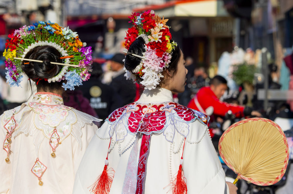  2024年1月26日，头戴簪花的游客在福建省泉州市蟳埔村游览。新华社记者 魏培全 摄