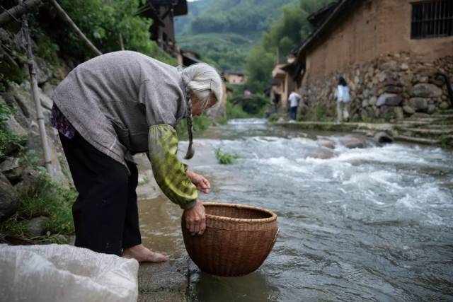 ▲松庄村，一位老奶奶在河边洗油菜籽