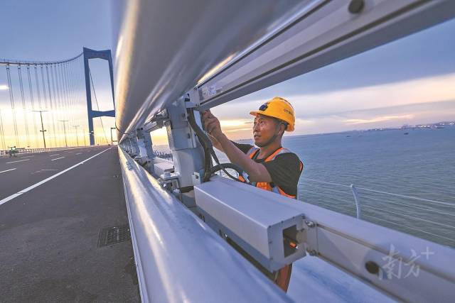 超1.5万名建设者参与了深中通道的建设。图为工人在深中大桥上安装灯光设施。