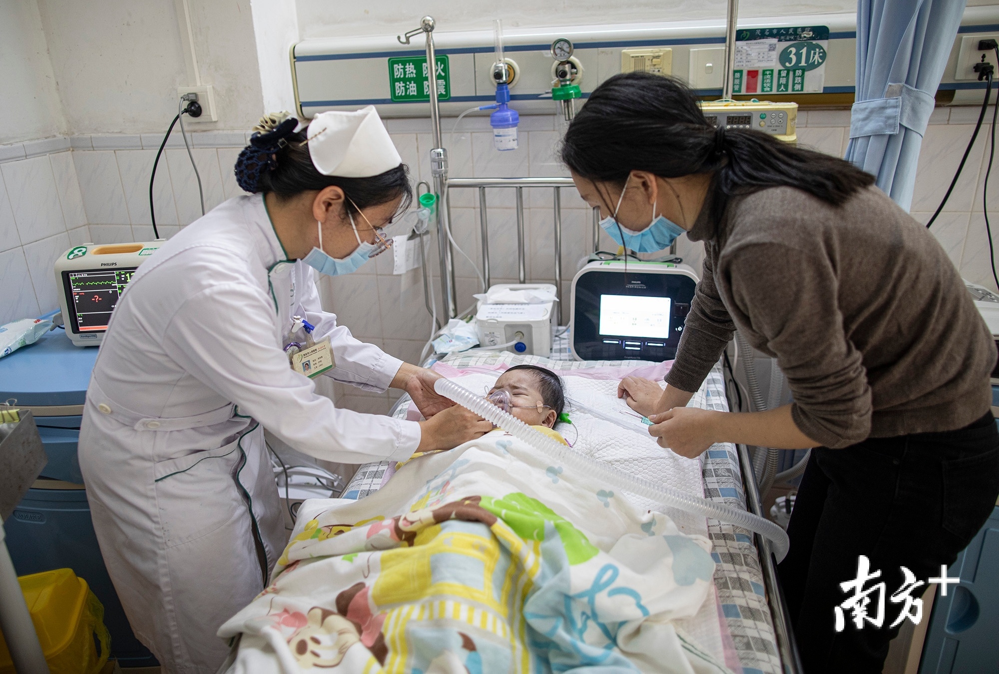 茂名市人民医院，杜佳协助护士对“米粒”进行吸痰护理。
