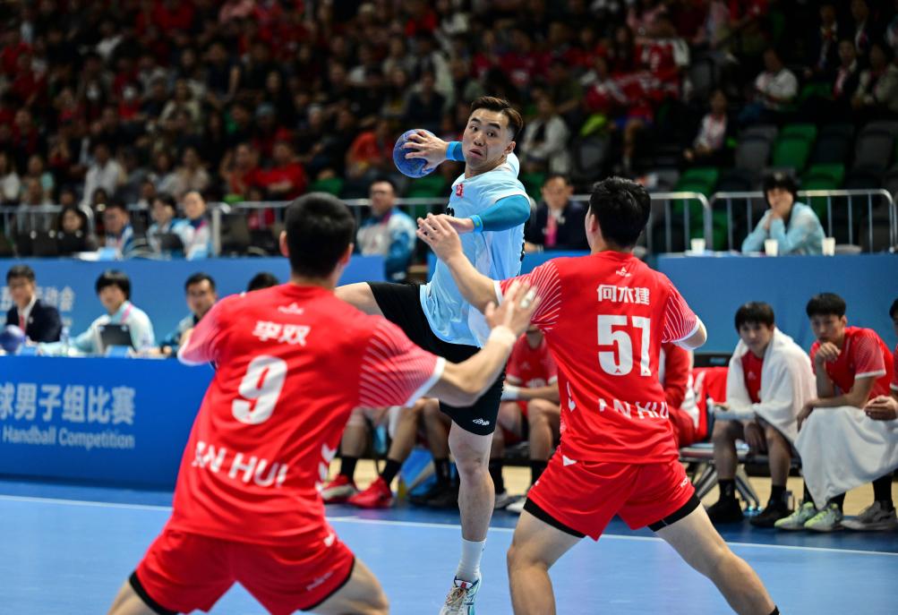 ↑11月8日，在香港进行的第十五届全国运动会男子手球半决赛中，香港队球员连润滔（中）在比赛中射门。