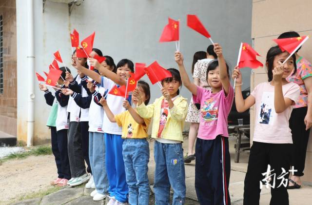 刚放学的小学生挥旗迎接陈冠锋。  