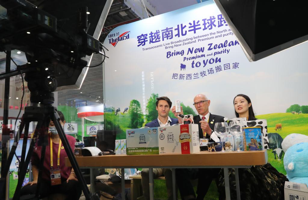 新西兰纽仕兰乳业有限公司执行总裁罗伊·范登克（中）在第三届进博会展台上搭建的网络直播间出镜带货。新华社记者方喆 摄