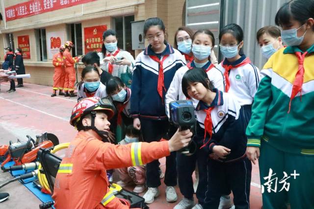 消防员向少先队员介绍红外线热成像仪的使用方法。