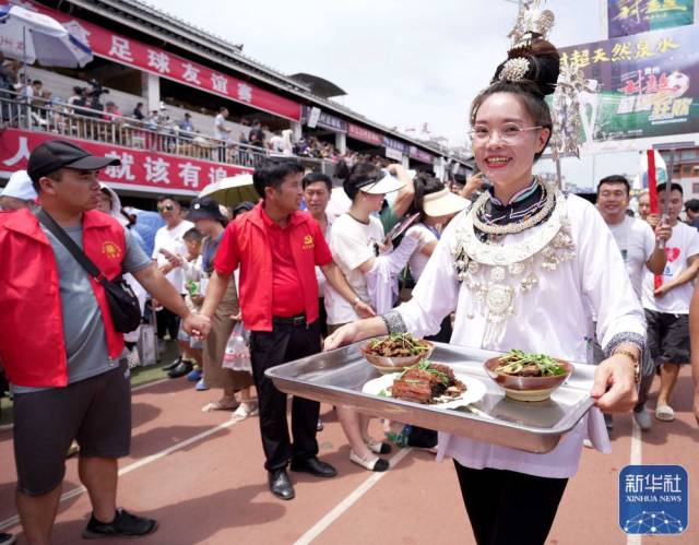 ↑工作人员进场时展示当地美食。新华社发（王炳真 摄）