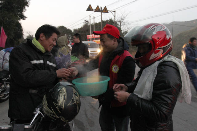2014年1月22日，梅州返乡摩托大军路过丰顺县兵营山顶，志愿者为歇息的摩托车大军提供热粥。资料图片