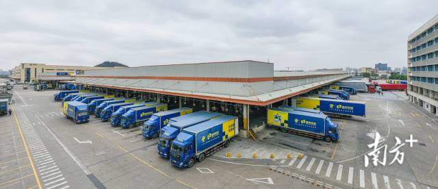 多辆货车正在德邦快递顺德枢纽中心装卸货。 