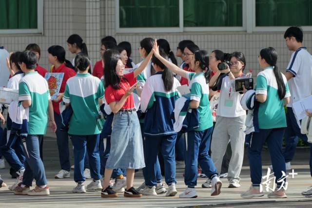 在佛山市第三中学考点，老师与同学们击掌，为他们加油鼓劲。