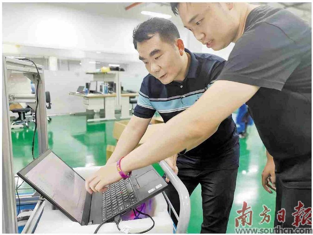 周斌（左）在指导学生调试设备。南方日报记者 唐亚冰 摄
