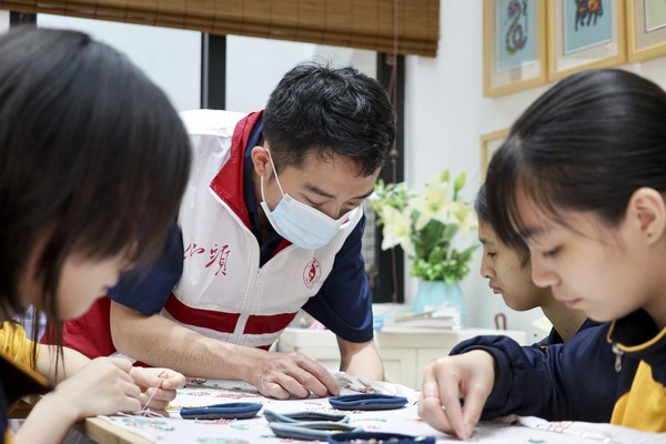 文化志愿者在汕头市聋哑学校指导学生为图案绣珠“上色”.jpg