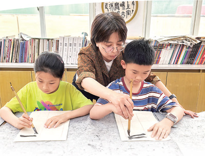 杭州春芽实验学校老师指导春假托管学生练习书法。人民日报记者 刘军国摄
