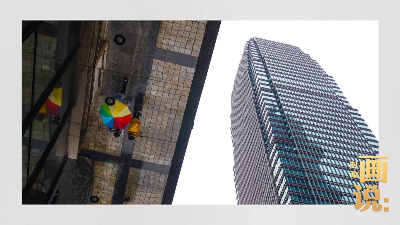 高楼大厦掩映下的解放碑步行街，行人的雨伞映照在玻璃幕墙上，留下一抹亮色。