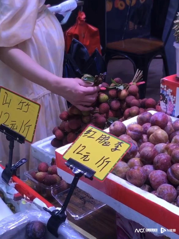 北亭村水果店一顾客正在挑选荔枝。